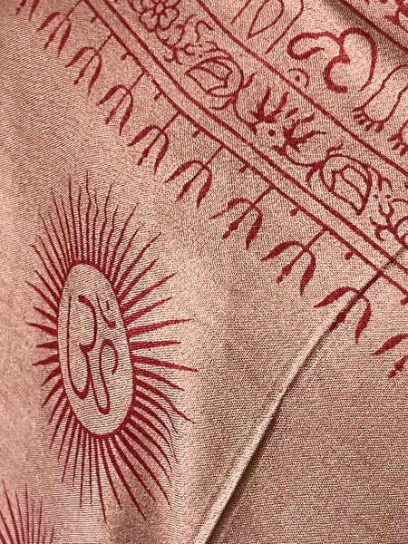 Detail of the Om mantra hand block print in dusty rose and maroon on soft cotton